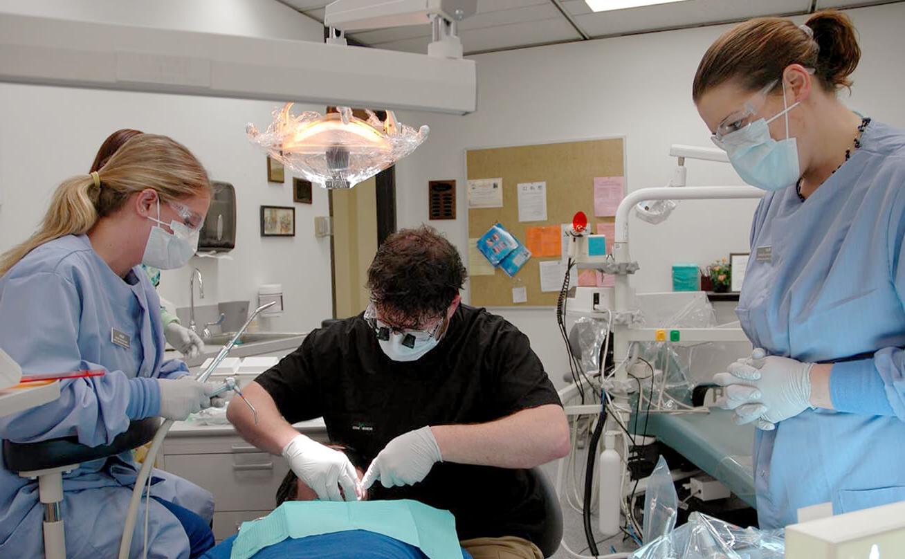 Three students practicing dental work on patient
